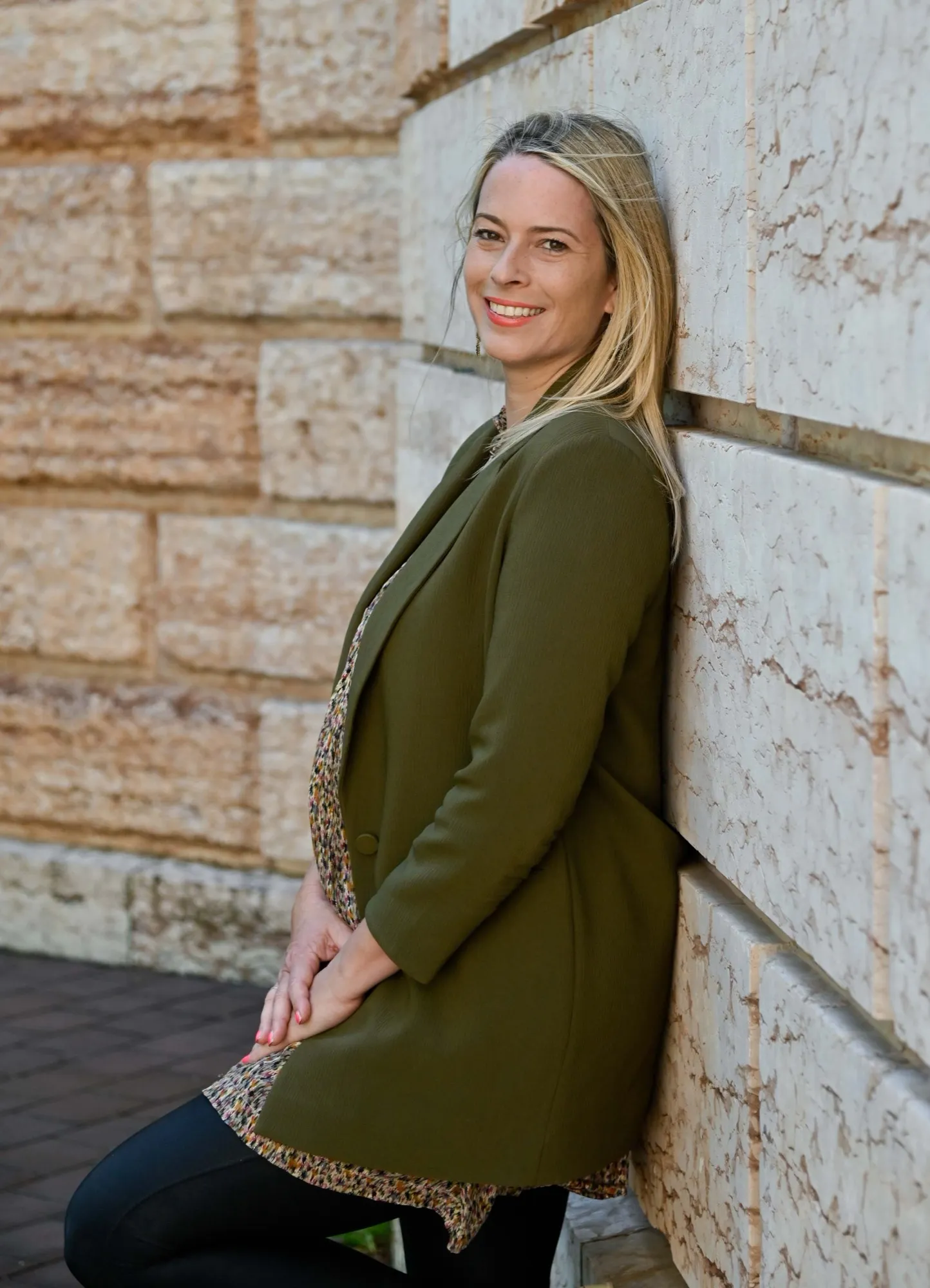 Bettina Hartung lehnt lächelnd an einer Sandsteinmauer